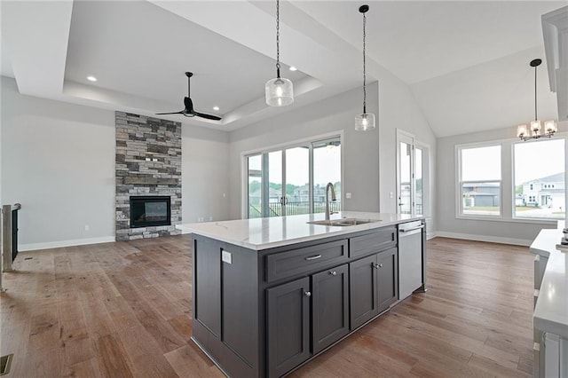 kitchen with open floor plan, a sink, a tray ceiling, a fireplace, and stainless steel dishwasher