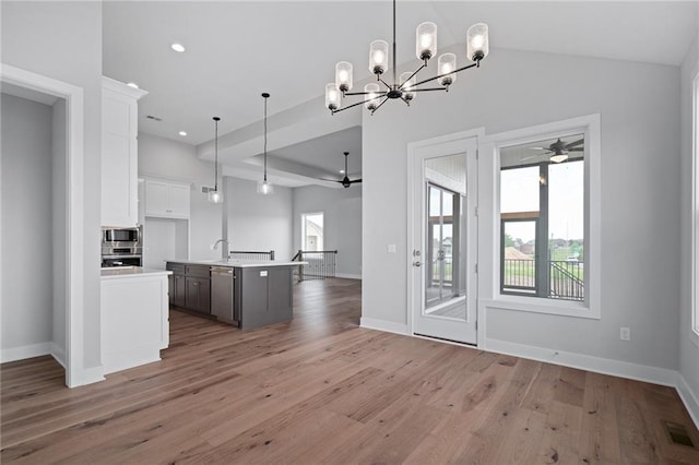 kitchen featuring ceiling fan with notable chandelier, stainless steel appliances, visible vents, open floor plan, and light countertops