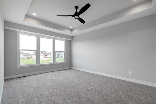 unfurnished room with ceiling fan, recessed lighting, carpet flooring, baseboards, and a tray ceiling