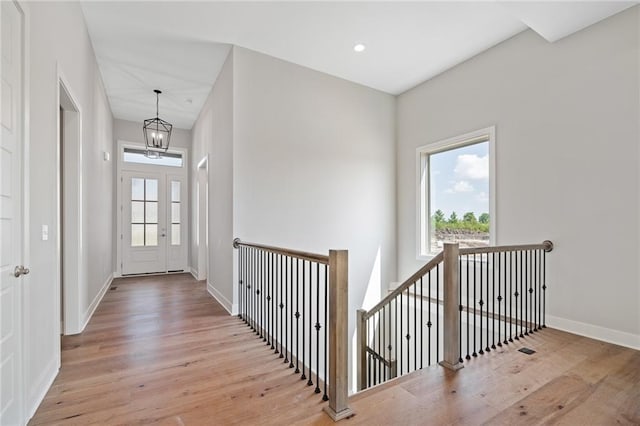 hall featuring baseboards, plenty of natural light, an upstairs landing, and light wood-style floors