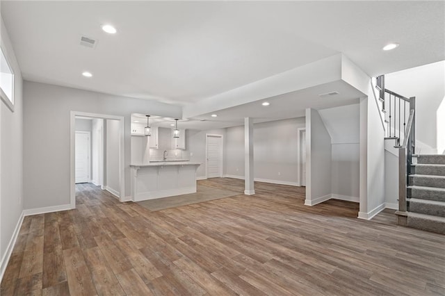 unfurnished living room featuring stairs, wood finished floors, visible vents, and recessed lighting