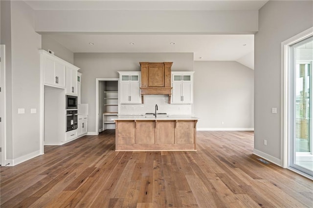 kitchen with tasteful backsplash, built in microwave, light countertops, hardwood / wood-style floors, and oven