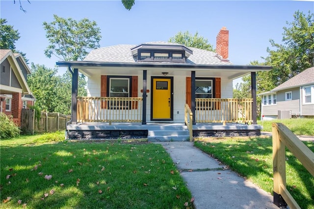 bungalow featuring cooling unit, a front lawn, and covered porch