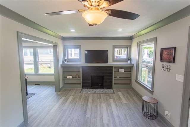 unfurnished living room featuring a fireplace, light wood-type flooring, and ceiling fan