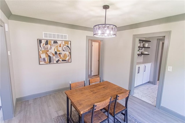 dining area featuring light wood-type flooring and a notable chandelier