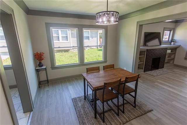 dining room with a brick fireplace, a notable chandelier, and light wood-type flooring