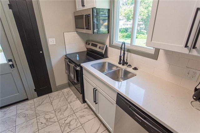 kitchen with white cabinets, appliances with stainless steel finishes, sink, and tasteful backsplash