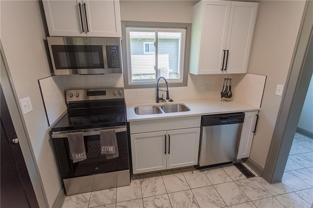 kitchen with stainless steel appliances, sink, decorative backsplash, and white cabinetry