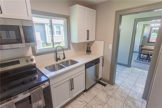 kitchen featuring white cabinets, appliances with stainless steel finishes, sink, and tasteful backsplash