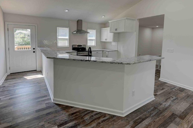 kitchen featuring wall chimney range hood, a wealth of natural light, dark hardwood / wood-style flooring, and white cabinetry