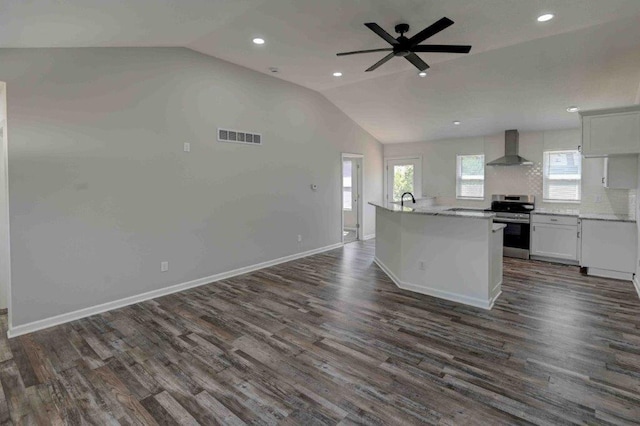 kitchen featuring dark wood-type flooring, stainless steel range oven, ceiling fan, wall chimney range hood, and white cabinets