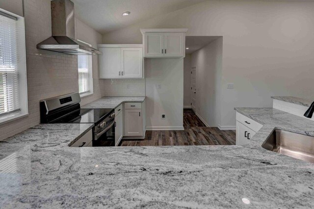 kitchen featuring electric stove, tasteful backsplash, dark hardwood / wood-style floors, lofted ceiling, and wall chimney range hood