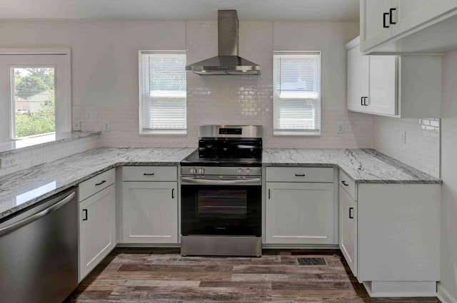 kitchen featuring appliances with stainless steel finishes, dark hardwood / wood-style floors, backsplash, and wall chimney exhaust hood