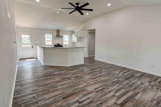 kitchen with dark hardwood / wood-style floors, wall chimney exhaust hood, lofted ceiling, ceiling fan, and white cabinets