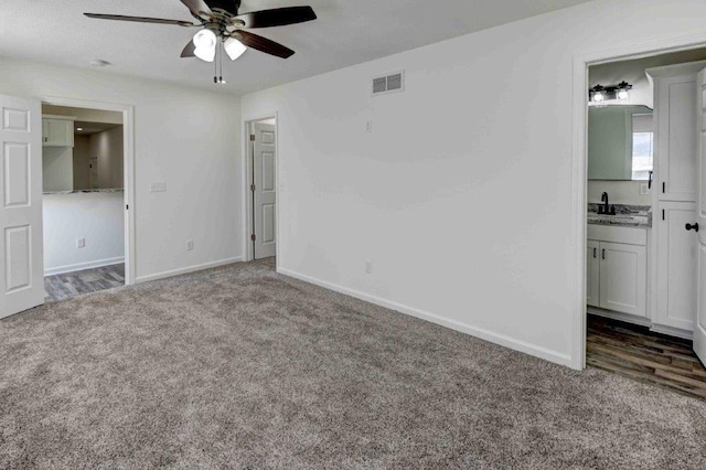 unfurnished bedroom with ceiling fan, dark colored carpet, sink, and ensuite bathroom