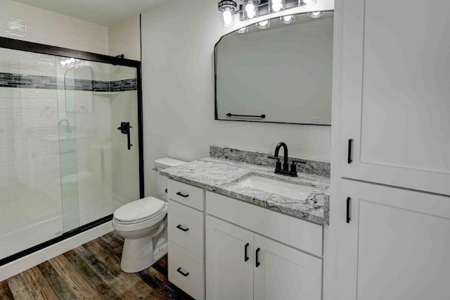 bathroom with vanity, toilet, hardwood / wood-style flooring, and an enclosed shower