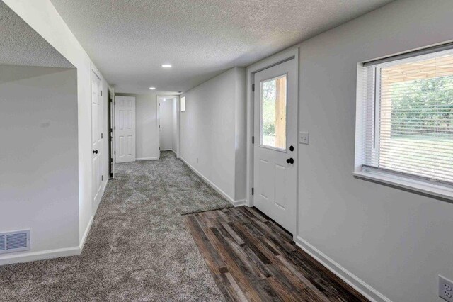 entryway with a textured ceiling and dark colored carpet