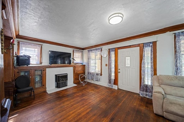 living room with a wealth of natural light, a textured ceiling, and dark hardwood / wood-style floors