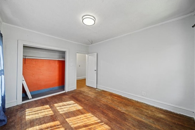 unfurnished bedroom featuring a closet, dark hardwood / wood-style floors, and crown molding