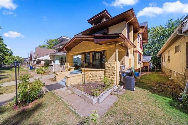 3917 Benton Blvd, Kansas City, MO 64130 - back of house with a porch, a lawn, stone siding, and stucco siding