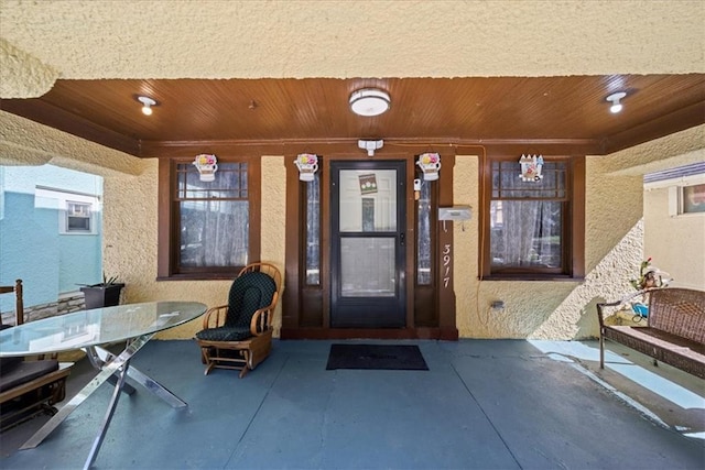3917 Benton Blvd, Kansas City, MO 64130 - doorway to property with covered porch, stucco siding, and outdoor dining space