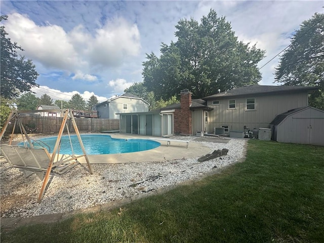 view of pool featuring a storage unit, a patio area, and a lawn