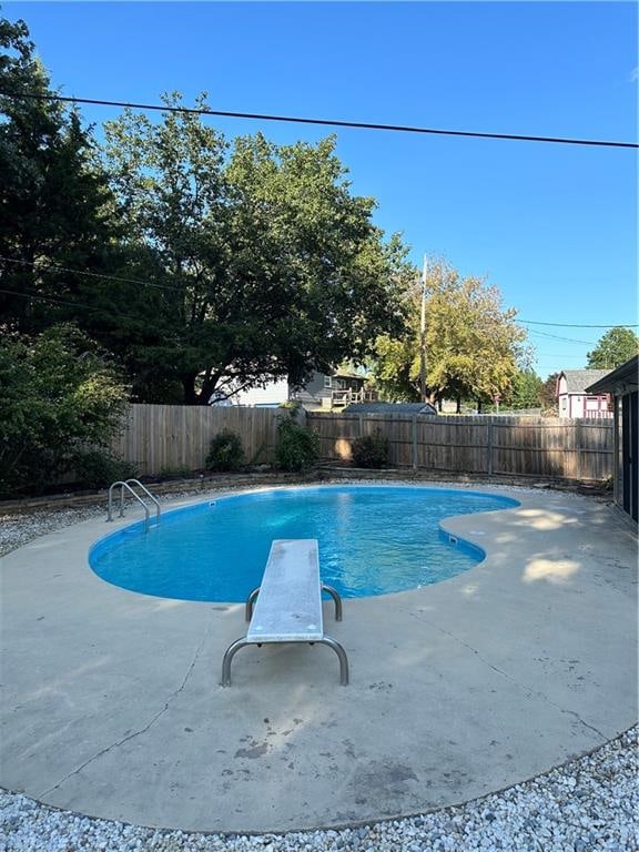 view of swimming pool featuring a diving board and a patio area