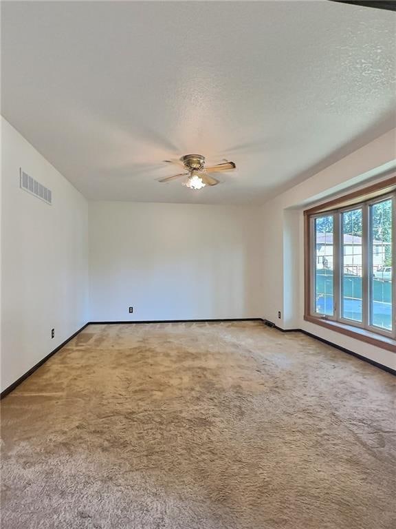 carpeted empty room with a textured ceiling and ceiling fan