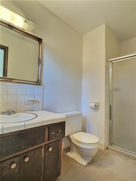 bathroom featuring tasteful backsplash, vanity, toilet, and a shower with shower door