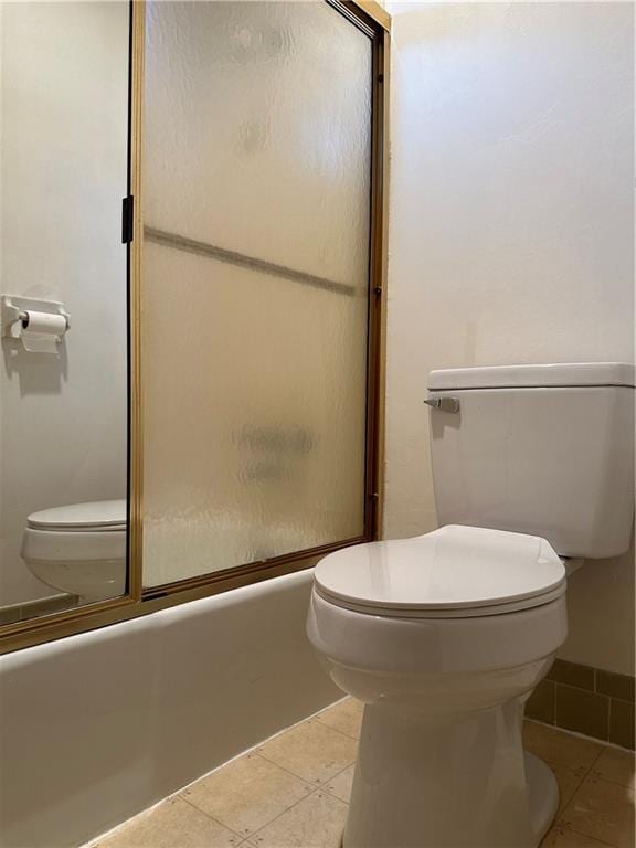 bathroom with bath / shower combo with glass door, tile patterned floors, and toilet