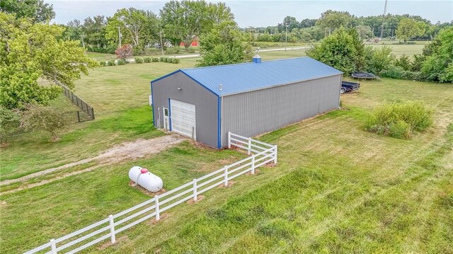 view of outdoor structure with a garage, a rural view, and a lawn