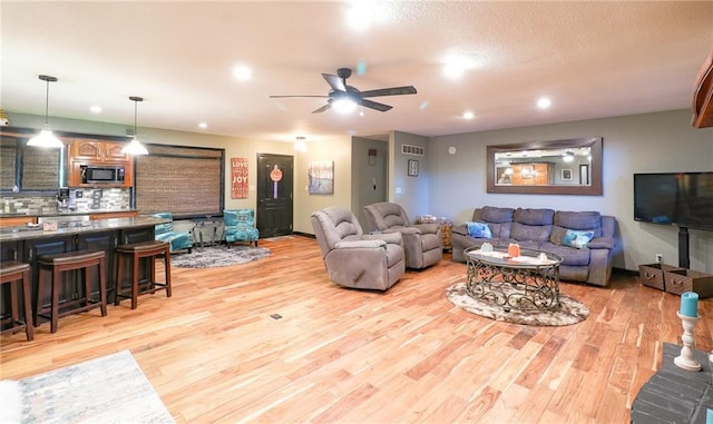 living room with ceiling fan, light wood-type flooring, visible vents, and recessed lighting