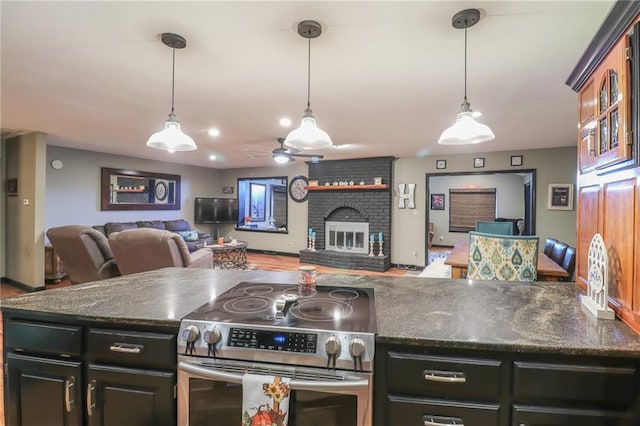 kitchen with a fireplace, a ceiling fan, open floor plan, hanging light fixtures, and stainless steel electric range oven