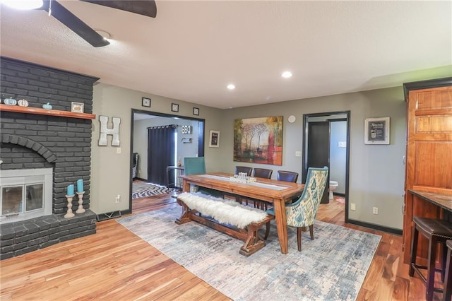 dining space featuring a fireplace, recessed lighting, ceiling fan, wood finished floors, and baseboards