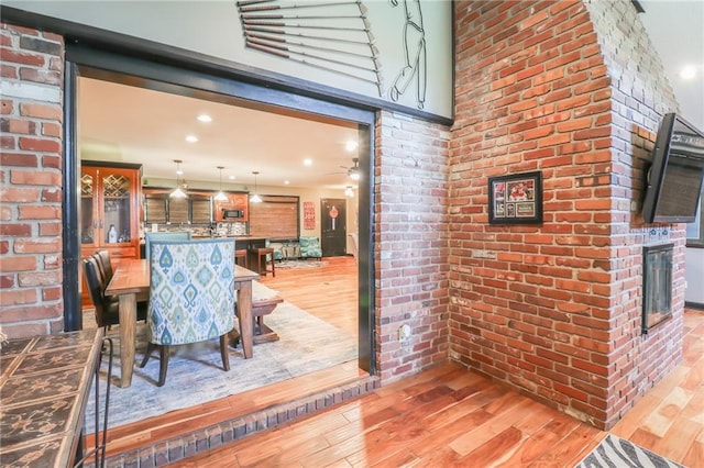 dining area featuring brick wall, a fireplace, and wood finished floors