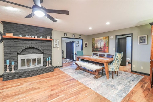 dining room with recessed lighting, a ceiling fan, a brick fireplace, wood finished floors, and baseboards