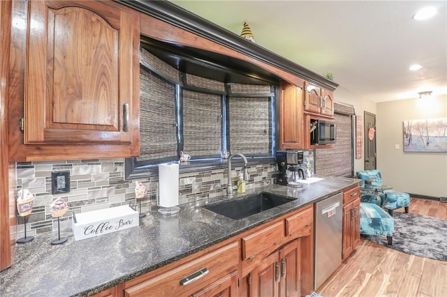 kitchen featuring brown cabinets, tasteful backsplash, light wood-style flooring, a sink, and dishwasher