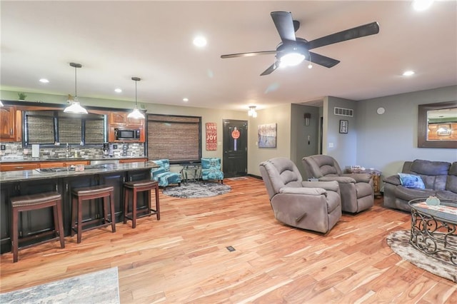 living area with ceiling fan, light wood-type flooring, visible vents, and recessed lighting