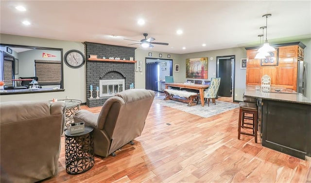 living room with light wood-style floors, a brick fireplace, a ceiling fan, and recessed lighting