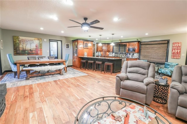 living area featuring light wood-type flooring, a ceiling fan, and recessed lighting