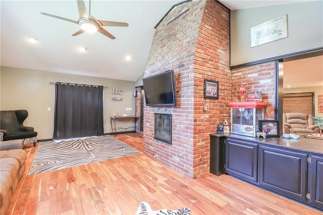 living area with high vaulted ceiling, a fireplace, and light wood finished floors