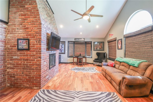 living area with recessed lighting, light wood-style floors, a ceiling fan, a brick fireplace, and high vaulted ceiling