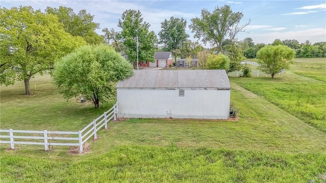 view of storm shelter with a rural view, fence, an outbuilding, and a yard