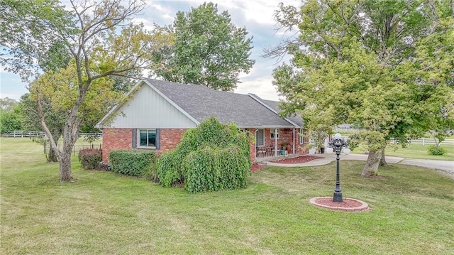 view of front of home with roof with shingles, a front yard, and brick siding