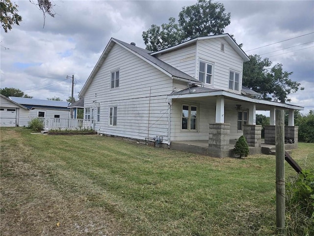 back of property with a garage, a yard, and covered porch