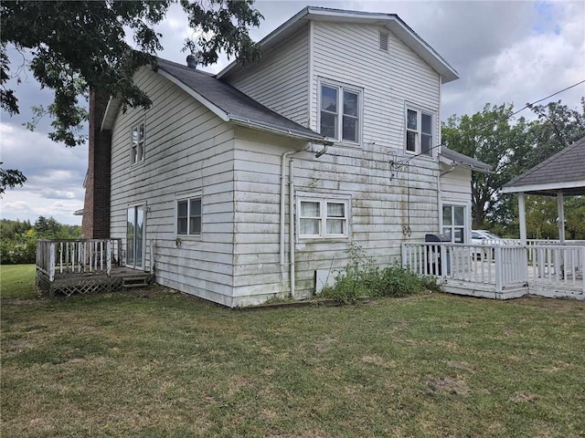 rear view of house with a wooden deck and a yard