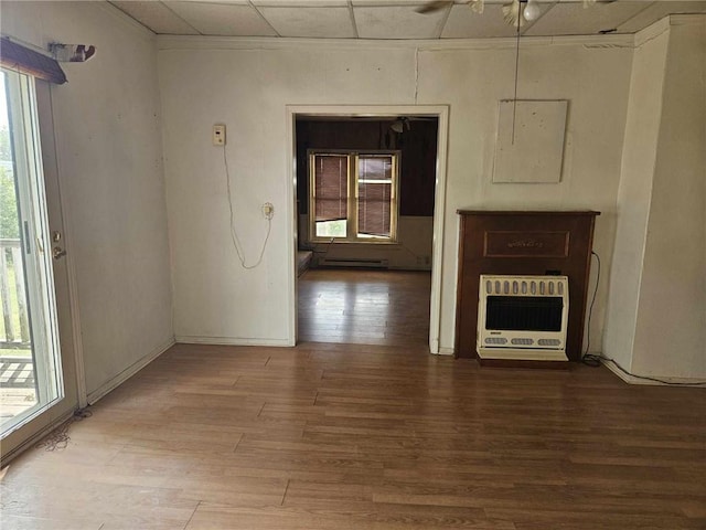 unfurnished living room with ceiling fan, hardwood / wood-style floors, and heating unit