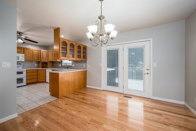 kitchen with ceiling fan with notable chandelier, white appliances, decorative light fixtures, kitchen peninsula, and light hardwood / wood-style floors