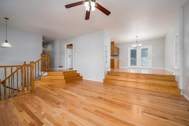 unfurnished living room with light wood-type flooring and ceiling fan with notable chandelier