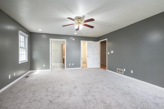 unfurnished bedroom with ensuite bath, light carpet, and ceiling fan